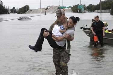 Houston Police SWAT officer Daryl Hudeck carries Catherine Pham and her 13-month-old son Aiden after rescuing them from their home surrounded by floodwaters from Tropical Storm Harvey Sunday, Aug. 27, 2017, in Houston.