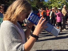 A woman views the solar eclipse through a homemade cereal box eclipse viewer.