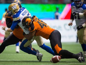 Winnipeg Blue Bombers' quarterback Matt Nichols, left, drops the ball as he's hit by B.C. Lions' Maxx Forde, right, and Mic'hael Brooks during the first half of a CFL football game in Vancouver, B.C., on Friday, July 21, 2017.