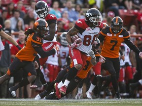 BC Lions' Josh Harris, left, and Matt Bucknor, right, look on as Calgary Stampeders' Jamal Nixon runs the ball during CFL pre-season football action in Calgary, Tuesday, June 6, 2017.