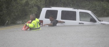 Wilford Martinez, right, waits to be rescued by Harris County Sheriff's Department Richard Wagner after his car got stuck in floodwaters from Tropical Storm Harvey on Sunday, Aug. 27, 2017, in Houston, Texas.