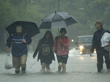 People walk in heavy rain as they evacuate floodwaters from Tropical Storm Harvey on Sunday, Aug. 27, 2017, in Houston, Texas.