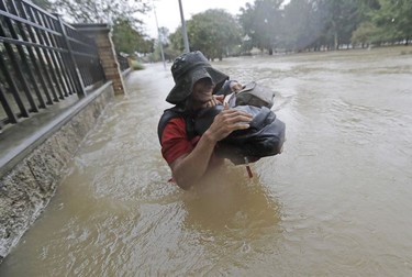 Residents wade through floodwaters from Tropical Storm Harvey Sunday, Aug. 27, 2017, in Houston, Texas.