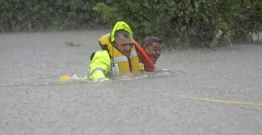 Wilford Martinez, right, is rescued from his flooded car along Interstate 610 in floodwaters from Tropical Storm Harvey on Sunday, Aug. 27, 2017, in Houston, Texas.