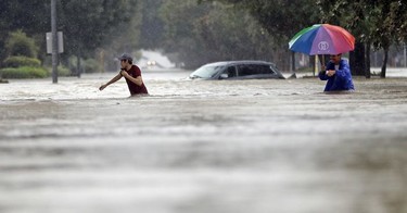 Moses Juarez, left, and Anselmo Padilla wade through floodwaters from Tropical Storm Harvey on Sunday, Aug. 27, 2017, in Houston, Texas.