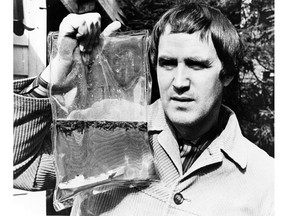 Iain Baxter, artist and president N.E. Thing Co., holding one of his bagged landscapes with water. Undated but likely late 1960s, early 1970s.