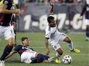 New England Revolution's Lee Nguyen, bottom, fouls Vancouver Whitecaps' Cristian Techera (13) during the first half of an MLS soccer game, Saturday, in Foxborough, Mass.