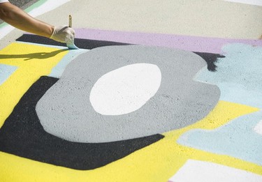 Jack Morris points a mural in a parking lot as part of the Vancouver Mural Festival.