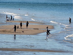 Vancouverites enjoy sunny weather and low tide at English Bay Beach in Vancouver, BC.