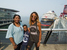 The North Shore Mountains and most of the North Vancouver shoreline are obscured by haze as Ruth Yakobu, right, of Seattle poses for pictures at Canada Place in Vancouver on Monday with her mother Phoebe and son Isaac, 8.
