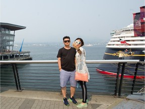 Tourists visit Canada Place in Vancouver, B.C., August 7, 2017. North Shore mountains are behind a cloud of smoke.