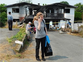 Esther Walls stands in front of her fire-damaged home on 128th Avenue near 103rd Street in Surrey on Monday.