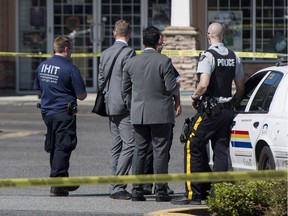RCMP and IHIT investigators talk in the parking lot of a strip mall on 128 Street after a body was found in a lane one Sunday morning in 2017.