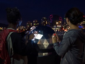 Two women playing with OH!, an interactive installation that lets you manipulate the lights of Science World.