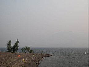 Thick smoke from wildfires fills the air as people stand on a beach on Kamloops Lake, west of Kamloops, on Tuesday.