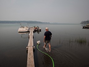 The same fire that destroyed dozens of homes near Ashcroft six weeks ago has now consumed structures in the Green Lake area almost 100 kilometres away. Jack Keough, who is defying a wildfire evacuation order, checks on a generator he's using to draw lake water to protect his property with sprinklers, in Green Lake, B.C., on Sunday, July 30, 2017.