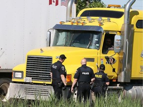 In this June 1, 2017 file photo, Windsor Police, LaSalle Police and OPP officers get a closer look at a commercial vehicle which was hauling broken debris in an uncovered industrial bin. Vancouver Police have launched a new campaign targeting unsafe commercial trucks and vans within Vancouver.