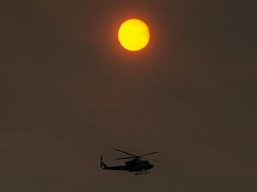 The sun is obscured by smoke from wildfires as an RCMP helicopter flies over Kelowna, B.C., on Tuesday September 15, 2017. THE CANADIAN PRESS/Darryl Dyck