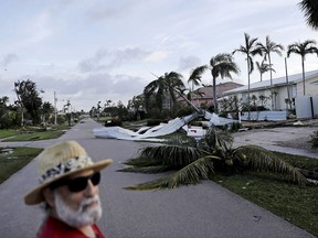 A fallen palm tree and a roof litters a street as Rick Freedman checks his neighborhood's damage from Hurricane Irma in Marco Island, Fla., Monday, Sept. 11, 2017. (AP Photo/David Goldman)