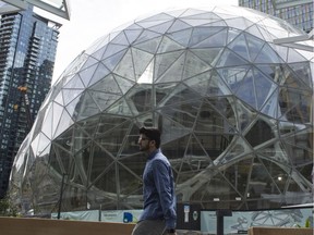 People walk past the signature glass spheres under construction at the Amazon corporate headquarters on June 16, 2017 in Seattle, Washington.  Vancouver plans a bid to become a second headquarters.