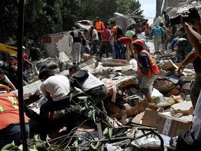 People remove debris of a building which collapsed after a quake rattled Mexico City on September 19, 2017. A powerful earthquake shook Mexico City on Tuesday, causing panic among the megalopolis' 20 million inhabitants on the 32nd anniversary of a devastating 1985 quake. The US Geological Survey put the quake's magnitude at 7.1 while Mexico's Seismological Institute said it measured 6.8 on its scale. The institute said the quake's epicenter was seven kilometers west of Chiautla de Tapia, in the neighboring state of Puebla.