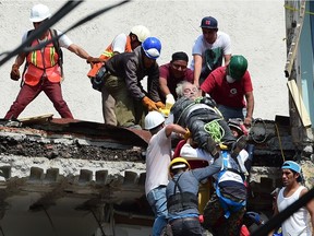 A man is pulled out of the rubble alive following a quake in Mexico City on September 19, 2017. A powerful earthquake shook Mexico City on Tuesday, causing panic among the megalopolis' 20 million inhabitants on the 32nd anniversary of a devastating 1985 quake. The US Geological Survey put the quake's magnitude at 7.1 while Mexico's Seismological Institute said it measured 6.8 on its scale. The institute said the quake's epicenter was seven kilometers west of Chiautla de Tapia, in the neighboring state of Puebla.