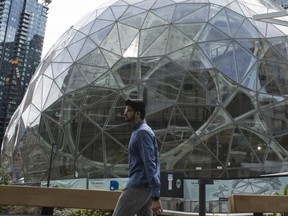 People walk past the signature glass spheres under construction at the Amazon corporate headquarters on June 16, 2017 in Seattle, Washington.