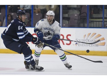 Vancouver Canucks Jonah Gadjovich plays with puck while pressured by Winnipeg Jets Logan Stanley.