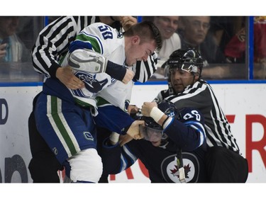 Vancouver Canucks Michael Carcone (left) grabs the visor of Winnipeg Jets Mathieu Sevigny while fighting during NHL preseason hockey action at the Young Stars Classic.