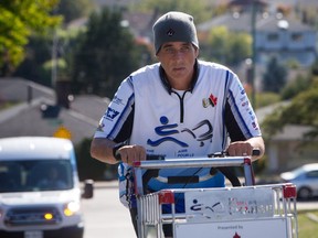 Joe Roberts, a former homeless youth, is pictured pushing his shopping cart up a street in Burnaby on Tuesday. His walk to raise awareness of homeless youth ends in Vancouver's Downtown Eastside on Friday.