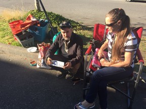 Sean and Brenda Murphy sit with what belongings they have next to where the RV they were living in was parked in East Vancouver before being towed by the city.