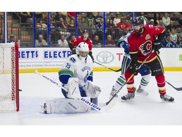 Vancouver Canucks goalie Michael DiPietro (left) makes a save and deflects the puck wide of the net as Calgary Flames Hunter Smith looks on during NHL preseason hockey Sunday, September 10