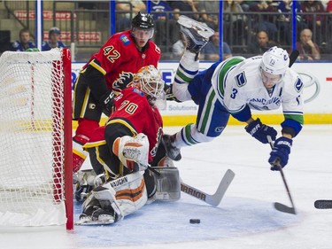 Vancouver Canucks Griffen Molino (right) goes airborne while trying to put the puck past Calgary Flames goalie Nick Schneider as Flames Juuso Valimaki looks on.