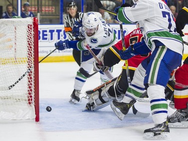 Vancouver Canucks Yan-Pavel Laplante (left) shovels the puck past Calgary Flames Nick Schneider for a goal.