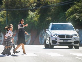 Schoolchildren, along with administrator Isabel Sankaran-Wee, cross Commercial Drive outside Stratford Hall independent school on Sept. 27 in Vancouver.