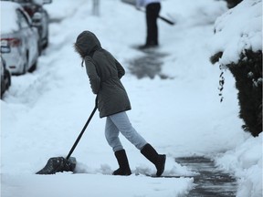 Residents on Dundas St shovel snow during an early morning power outage in Vancouver, BC., December 19, 2016.