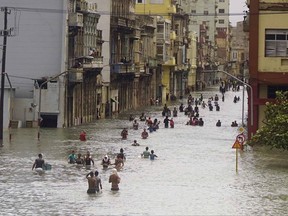 People move through flooded streets in Havana after the passage of Hurricane Irma, in Cuba, Sunday, Sept. 10, 2017. The powerful storm ripped roofs off houses, collapsed buildings and flooded hundreds of miles of coastline after cutting a trail of destruction across the Caribbean. Cuban officials warned residents to watch for even more flooding over the next few days. (AP Photo/Ramon Espinosa)