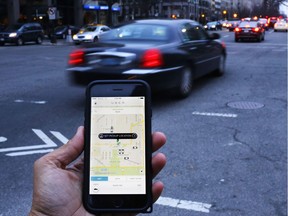 This file photo taken on March 25, 2015 shows an UBER application being shown as cars drive by in Washington, DC.