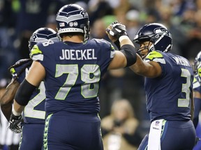 Quarterback Russell Wilson #3 of the Seattle Seahawks celebrates his 23 yard touchdown with offensive tackle Luke Joeckel #78 in the third quarter of the game at CenturyLink Field on October 1, 2017 in Seattle, Washington.