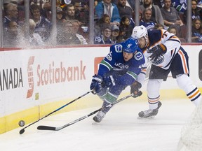 Derek Dorsett #15 of the Vancouver Canucks reaches for the puck after getting checked by Oscar Klefbom #77 of the Edmonton Oilers in NHL action on October, 7, 2017 at Rogers Arena in Vancouver, British Columbia, Canada.