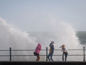 People run from a wave whipped up by Hurricane Ophelia as it crashes over the seafront in Penzance on Oct. 16 in Cornwall, England. Hurricane Ophelia comes exactly 30 years after the Great Storm of 1987.