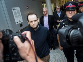 Joshua Boyle, left, gets a police escort after speaking to the media after arriving at the airport in Toronto on Friday, October 13, 2017. Boyle, His wife and and three children had been held hostage for five years by the Taliban-linked Haqqani network in Afghanistan.