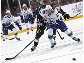 Defenceman Troy Stecher of the Vancouver Canucks pursues a loose puck with Kyle Clifford of the Los Angeles Kings hot on his heels.