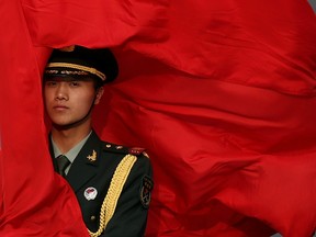The wind blows a red flag onto the face of an honour guard before a welcome ceremony outside the Great Hall of the People on April 9, 2013 in Beijing, China.