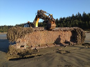 A Japanese skiff covered with sea life is recovered on Long Beach.