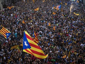 People wave "estelada" or pro independence flags outside the Palau Generalitat in Barcelona, Spain, after Catalonia's regional parliament passed a motion with which they say they are establishing an independent Catalan Republic, Friday, Oct. 27, 2017. (AP Photo/Emilio Morenatti)
