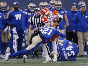 Winnipeg Blue Bombers' Brandon Alexander (21) hits B.C. Lions quarterback Jonathon Jennings (10) as he tries to run for yards during second half CFL action in Winnipeg, Saturday.