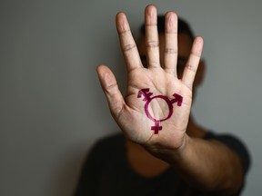 Closeup of a transgender symbol painted on the palm of a young person.