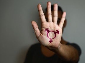 closeup of a transgender symbol painted in the palm of the hand of a young caucasian person