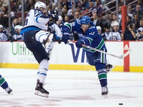 Bo Horvat of the Vancouver Canucks, right, checks Mark Scheifele of the Winnipeg Jets during NHL action in Vancouver on Oct. 12.